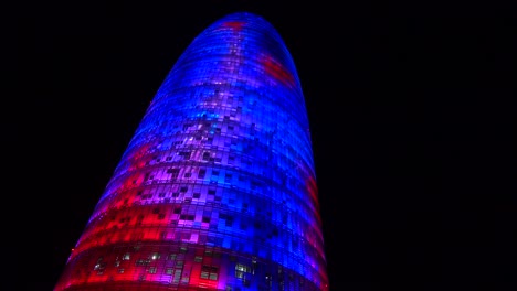 Remarkable-blue-and-red-skyscraper-at-night-in-Barcelona-Spain