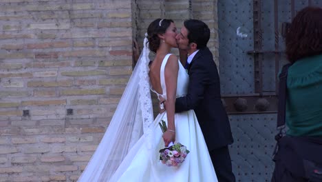 A-bride-and-groom-kiss-on-a-public-street-while-a-photographer-snaps-pictures