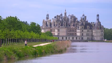 Long-view-down-a-canal-to-the-beautiful-chateau-of-Chambord-in-the-Loire-Valley-in-France