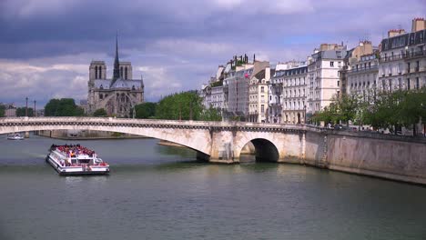 Ein-Flussschiff-Fährt-Unter-Brücken-In-Der-Nähe-Der-Kathedrale-Notre-Dame-In-Paris