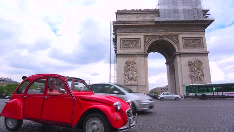 A-vintage-red-Citroen-sits-in-front-of-the-Arc-De-Triomphe-in-Paris