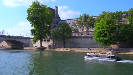A-point-of-view-of-asmall-boat-from-a--bateaux-mouche-riverboat-traveling-along-the-Seine-River-in-Paris
