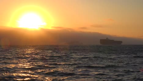 A-cargo-ship-travels-in-the-distance-across-the-high-seas-at-sunset