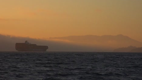 A-cargo-ship-travels-in-the-distance-across-the-high-seas-at-sunset-1