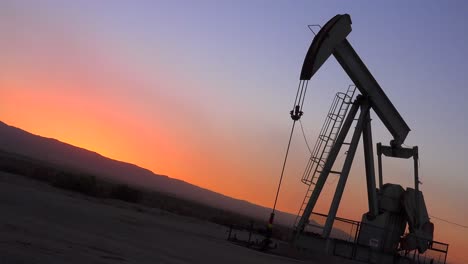 An-oil-derrick-pumps-against-the-horizon-at-dusk-1