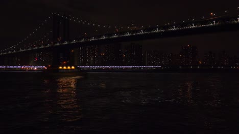 Die-Brooklyn-Bridge-Bei-Nacht-Mit-Der-Skyline-Von-New-York-City-Im-Hintergrund-Und-Der-U-Bahn-Vorbei