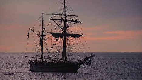 A-tall-clipper-ship-sails-at-sunset-with-sailors-on-the-riggings