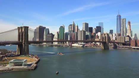 Nice-establishing-shot-of-New-York-City-financial-district-with-Brooklyn-Bridge-foreground-and-boats-passing-under