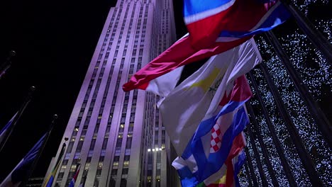 Tilt-up-shot-to-reveal-Rockefeller-Center-in-New-York-City-at-night-with-flags-flying