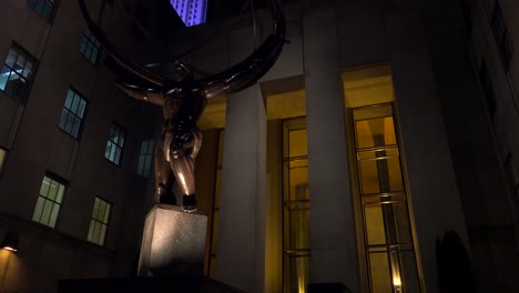 Tilt-up-shot-to-reveal-Rockefeller-Center-in-New-York-City-at-night-with-Atlas-statue-in-foreground
