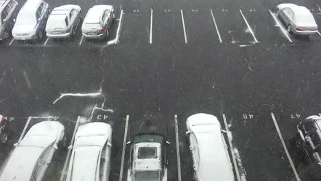 A-high-angle-view-of-snow-falling-on-a-parking-lot-with-cars