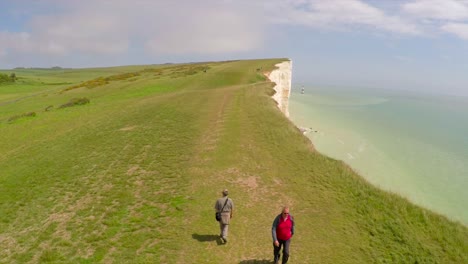 Aerial-shot-of-people-walking-along-the-White-Cliffs-of-Dover-at-Beachy-Head-England