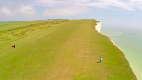 Aerial-shot-of-people-walking-along-the-White-Cliffs-of-Dover-at-Beachy-Head-England-1
