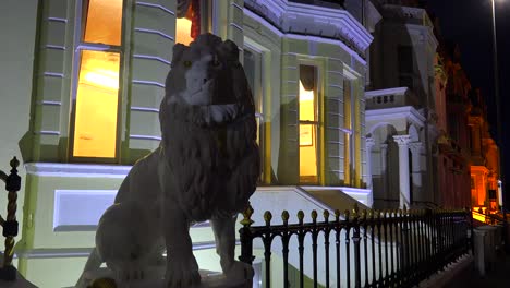 A-lion-statue-sits-in-front-of-an-elegant-row-of-houses-in-a-British-town