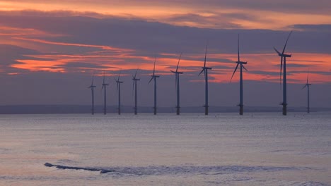 A-wind-farm-generates-electricity-along-a-coastline-at-sunset-2