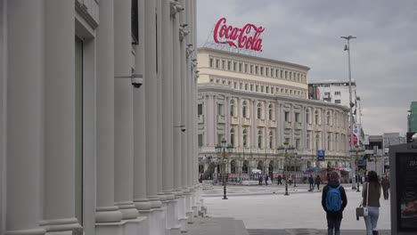 Pedestrians-walk-in-downtown-Skopje-Macedonia-with-Coca-Cola-building-background