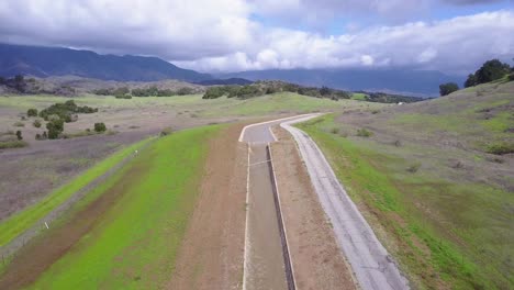 Good-aerial-shot-of-an-aqueduct-flowing-through-the-desert-and-mountains-of-California-2