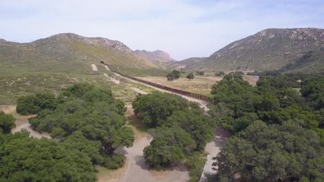 Forward-aerial-shot-of-US-Mexico-border-wall-in-a-rural-area