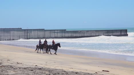 Leute-Reiten-Pferde-Am-Strand-Am-US-Mexiko-Grenzzaun-Im-Pazifischen-Ozean-Zwischen-San-Diego-Und-Tijuana