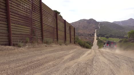 A-Border-Patrol-vehicle-moves-along-the-US-Mexico-border-wall-fence-in-the-California-desert