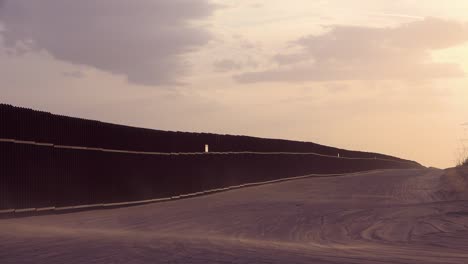 Staub-Weht-Bei-Sonnenuntergang-An-Der-Grenzmauer-An-Der-US-Mexiko-Grenze-In-Der-Nähe-Von-Imperial-Sand-Dunes-California-1