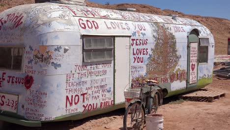 A-trailer-painted-with-Bible-verses-sits-in-the-desert-in-Slab-City-California
