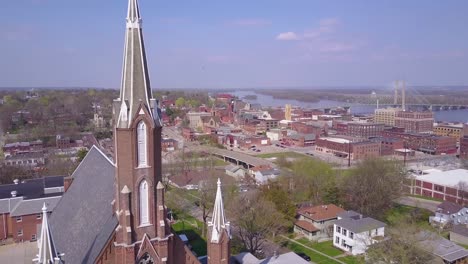 Aerial-shot-over-small-town-America-church-reveals-Burlington-Iowa-with-Mississippi-River-background