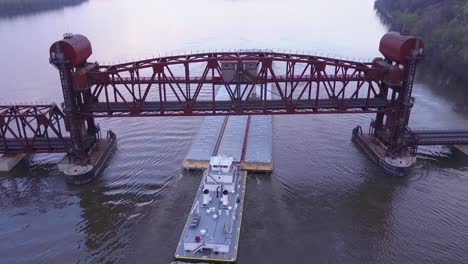 A-beautiful-aerial-of-a-barge-traveling-on-the-Mississippi-River-under-a-large-steel-drawbridge