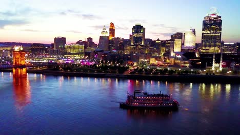 A-beautiful-evening-aerial-shot-of-Cincinnati-Ohio-with-riverboat-and--bridge-crossing-the-Ohio-River-foreground