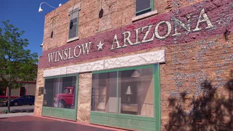 Establishing-shot-of-downtown-Winslow-Arizona-with-mural-depicting-a-flatbed-Ford