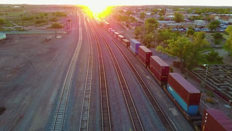 High-aerial-over-a-freight-train-full-of-containers-for-export-heading-into-the-sunset