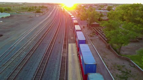 High-aerial-over-a-freight-train-full-of-containers-for-export-heading-into-the-sunset-1
