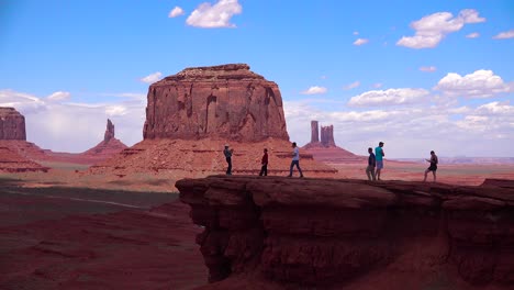 Tourists-walk-on-an-outcrop-in-front-of-Monument-Valley-1