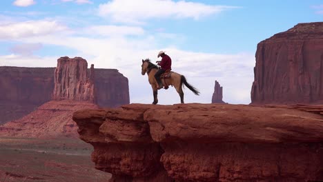 A-cowboy-sits-on-a-horse-on-a-cliff-in-Monument-Valley-Utah