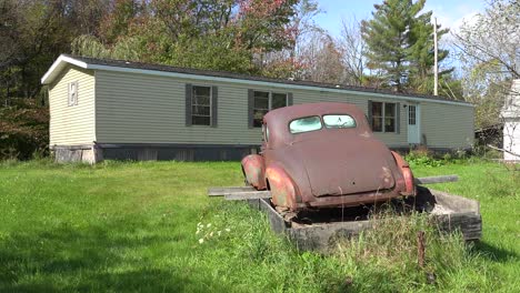 An-abandoned-car-sits-on-blocks-outside-a-trailer-home-in-rural-America