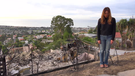A-woman-stands-in-front-of-a-burned-home-after-the-Thomas-fire-in-Ventura-California