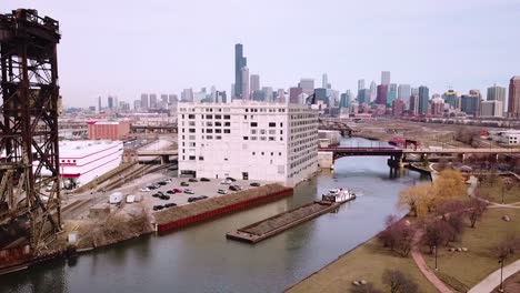 Aerial-over-a-barge-traveling-along-the-Chicago-River-with-city-of-Chicago-skyline-background