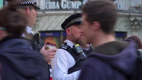 Zwei-Londoner-Bobby-Polizisten-Trinken-Kaffee-Und-Beobachten-Fußgänger-In-Einem-Belebten-Touristenviertel