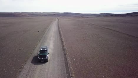 Very-good-aerial-of-a-black-van-traveling-on-a-dirt-road-across-the-highland-interior-of-Iceland