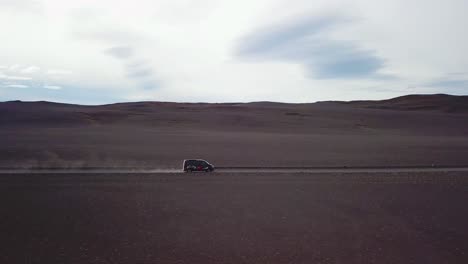 Very-good-aerial-of-a-black-van-traveling-on-a-dirt-road-across-the-highland-interior-of-Iceland-1