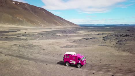Aerial-of-a-rare-pink-Land-Rover-101-driving-through-the-outback-highlands-of-desolate-Iceland-3