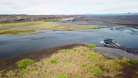 Aerial-over-a-black-van-driving-through-a-river-in-the-highlands-of-Iceland