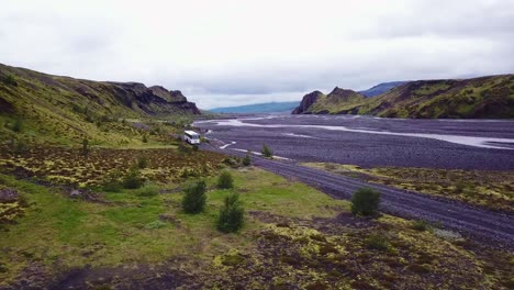 Aerial-over-a-bus-driving-beside-a-river-in-the-highlands-of-Iceland