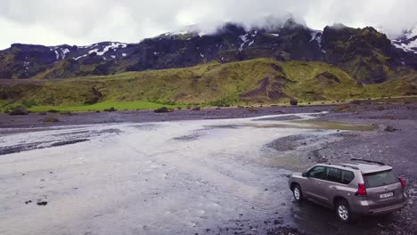 Vista-Aérea-over-a-Toyota-4x4-conduciendo-through-a-río-in-the-highlands-of-Iceland