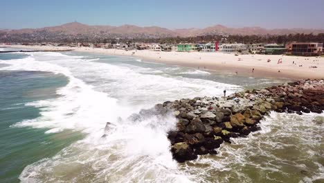 Aerial-of-a-man-fishing-off-a-breakwater-during-a-big-ocean-swell-with-large-waves-off-Ventura-harbor-California-1