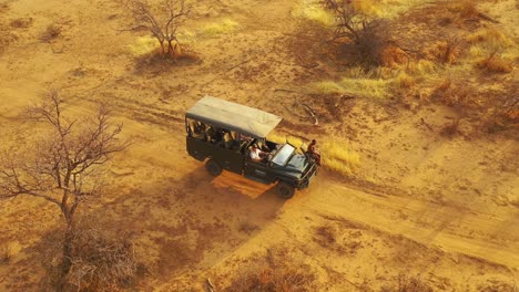 Ausgezeichnete-Antenne-Eines-Safari-Jeeps,-Der-Auf-Den-Ebenen-Afrikas-Im-Erindi-Wildreservat-In-Namibia-Reist,-Mit-Einem-Einheimischen-San-Tribal-Spotter-Führer,-Der-Auf-Der-Vorderseite-Sitzt-Und-Wildtiere-Beobachtet-2