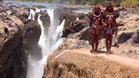 Tilt-up-from-Epupa-Falls-in-Namibia-reveals-two-Himba-tribal-woman