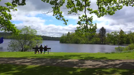 Leute-Sitzen-Auf-Einer-Bank-Und-Genießen-Die-Landschaft-Am-Loch-Lomand-Schottland