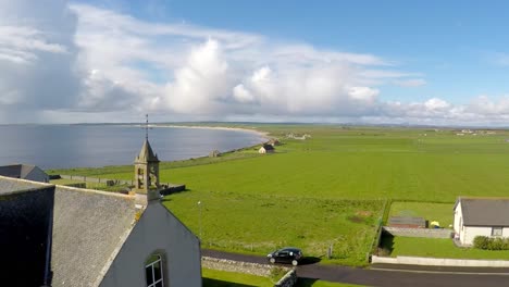 An-vista-aérea-shot-over-a-pretty-church-along-the-abandoned-coastline-of-Northern-Scotland