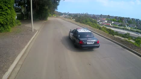 An-aerial-shot-over-a-police-car-traveling-on-a-road